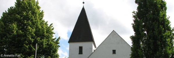 Hoffnungskirche Buchloe mit grünen Bäumen im Vordergrund